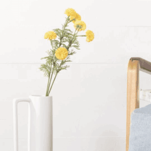 Yellow flowers in a white vase on a minimalistic white surface.